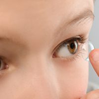 105660661 - little child putting contact lens into his eye, closeup